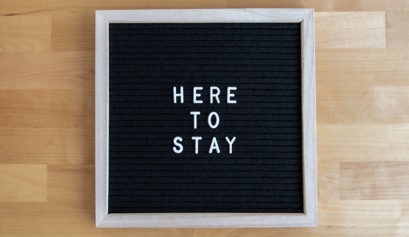 The words "Here to Stay" on a felt, framed letterboard