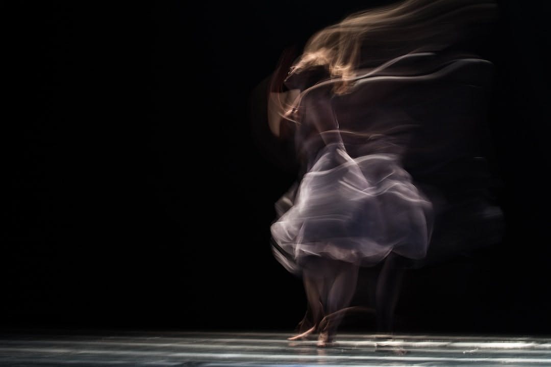 Woman dancing with motion blur in front of a black backdrop